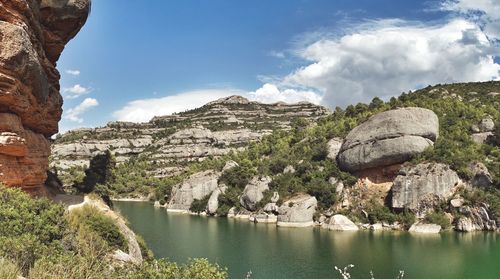 Scenic view of river by mountains against sky