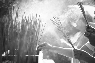 Close-up of human hands holding burning incense stick 