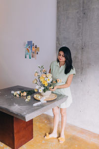 Full length, woman of indian ethnicity, working in a ikebana centerpiece 