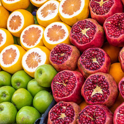 Sales stand for juice of apples, oranges and pomegranates with sliced fruits.