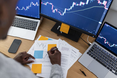 Young trader making strategy on paper working late night at home office