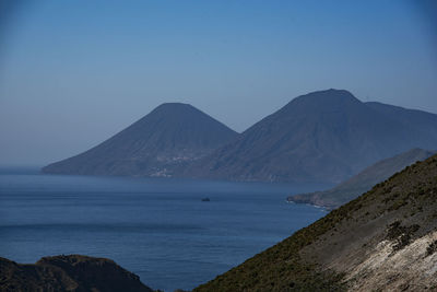 Scenic view of sea and mountains against clear sky