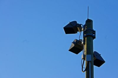 Low angle view of telephone pole against clear blue sky