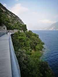 Scenic view of sea by mountain against sky