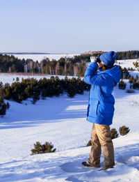 Rear view of man standing on snow covered field