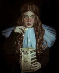 Portrait of beautiful model having popcorn against black background