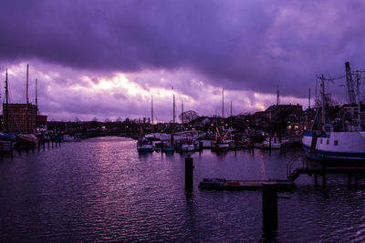 Sailboats in harbor against dramatic sky