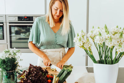 Young woman standing by plants in kitchen