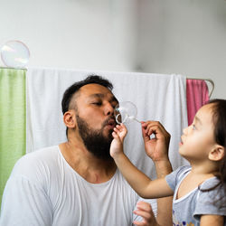 Girl playing father blowing bubbles