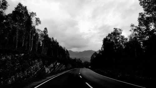 Road by trees against sky