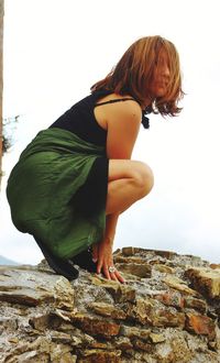 Side view of woman on rock against sky