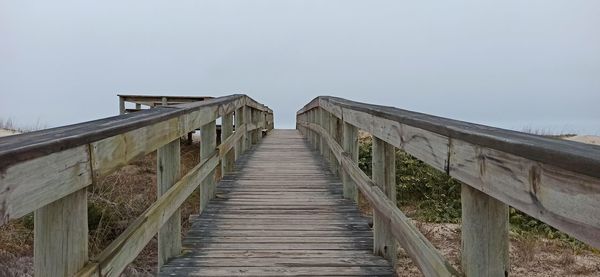 Wooden footbridge against clear sky