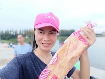 Portrait of a smiling young woman holding pink outdoors