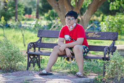 Portrait of boy sitting on bench in park