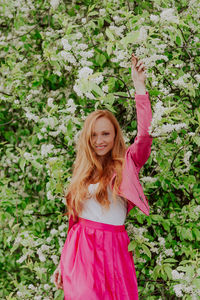 Portrait of smiling woman standing by plants