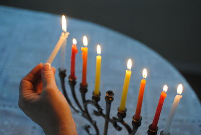 Cropped image of person lighting candles on table