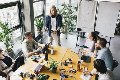 High angle view of male and female computer programmers discussing in meeting at office