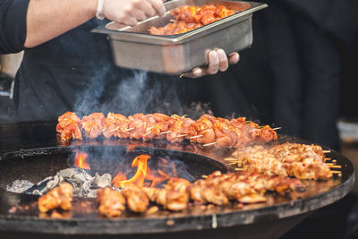 Preparing chicken meat skewers, grilled or roasted in a barbecue on an open fire and flames