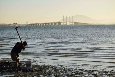 Silhouette of man by sea at sunset