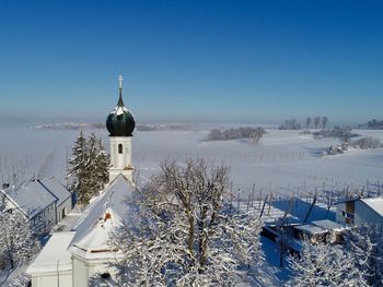 Church by building against blue sky during winter