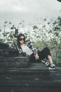 Young woman photographer holding a camera sitting on the stairs