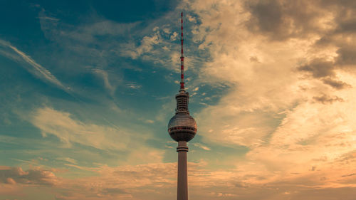 Low angle view of communications tower against cloudy sky
