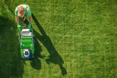 Man with lawn mower on field