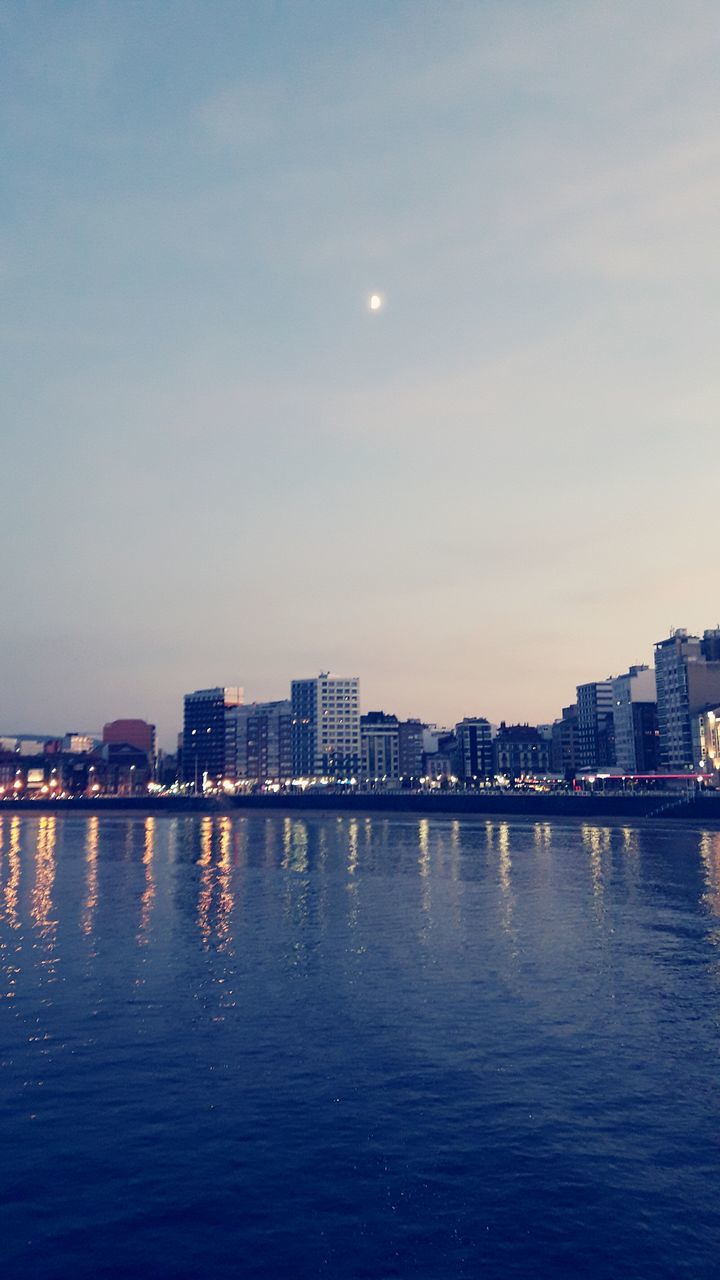 architecture, building exterior, skyscraper, city, water, cityscape, sky, built structure, river, waterfront, reflection, no people, illuminated, outdoors, sunset, nature, urban skyline, night, moon, travel destinations, modern, beauty in nature