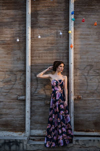 Full length of woman standing against closed shutter