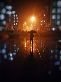 Full length of woman standing in illuminated city at night