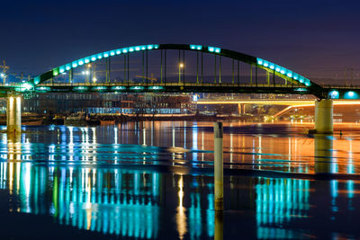 Illuminated bridge over river in city at night