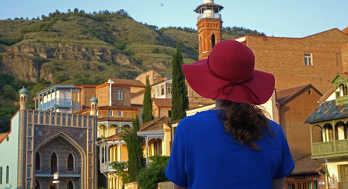 Rear view of woman standing by buildings against mountain