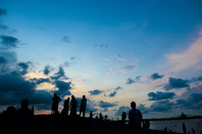 Silhouette people on beach against sky during sunset