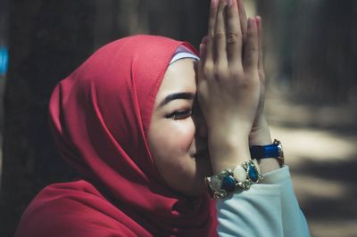Close-up of woman in hijab with hands clasped
