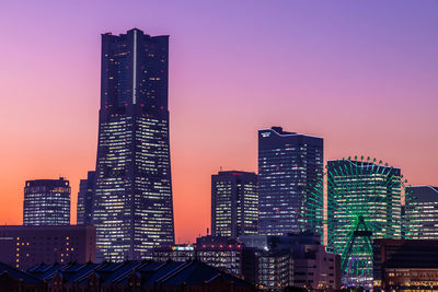 Illuminated buildings in city against sky