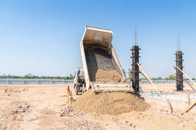 A truck pours sand onto a construction site. ingredient cement.