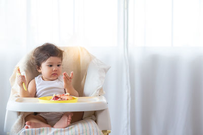 Full length of cute baby girl sitting at home