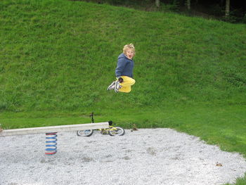 Side view of boy shouting while jumping from spring ride at park