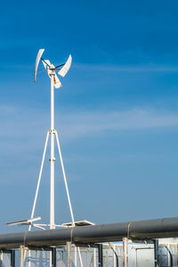 Low angle view of wind turbine against blue sky