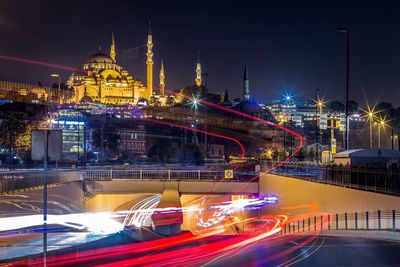 Light trails road leading towards tunnel against blue mosque