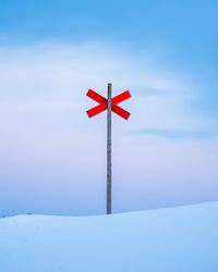 Red flag on snow covered field against sky