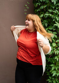 Young woman looking away while standing against wall