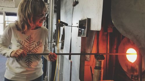 Woman holding metal rod while standing by fire 