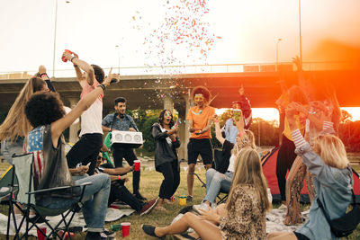 Happy friends dancing in musical event against sky in summer