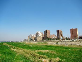 Buildings on field against clear blue sky
