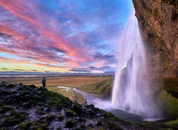 Scenic view of waterfall against cloudy sky