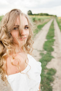 A young girl with a model appearance, in denim trousers and a white blouse in a sunflower field