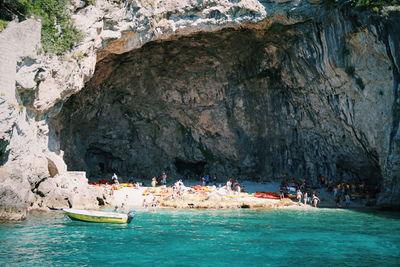 People by sea against cliff