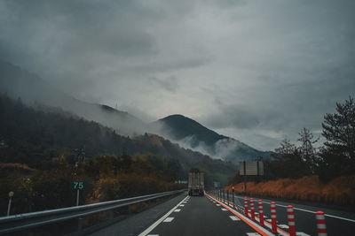 Road leading towards mountains against sky