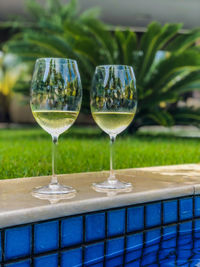 Close-up of wineglass on table at swimming pool